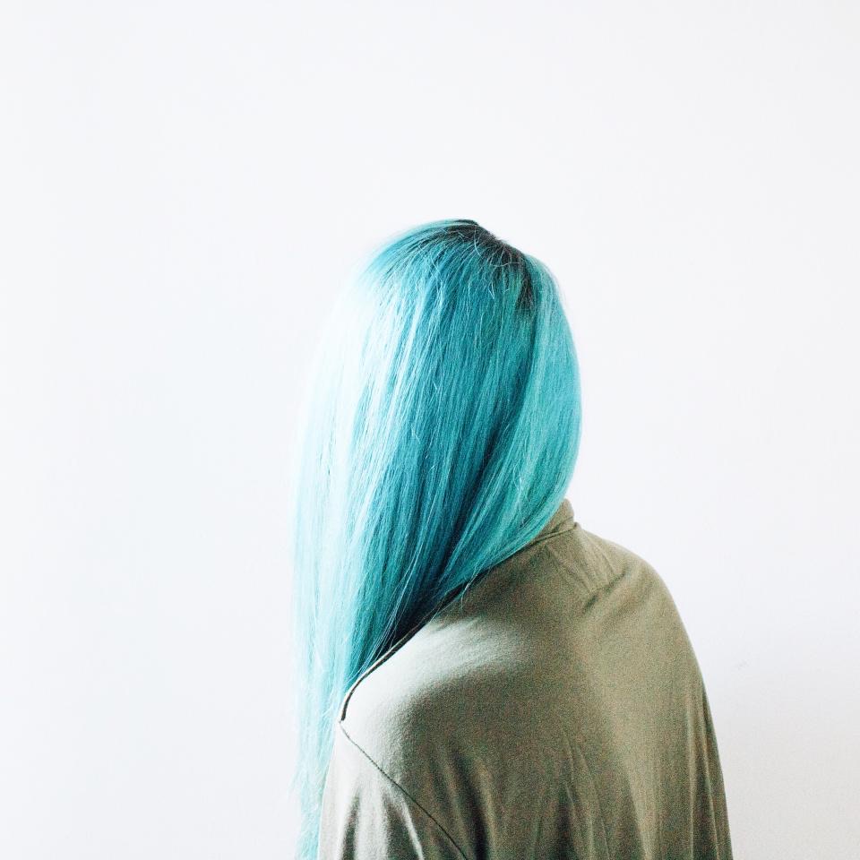 ผู้หญิงผมสีฟ้าอมเขียวหันหลัง ใส่เสื้อสีเขียวมะกอก